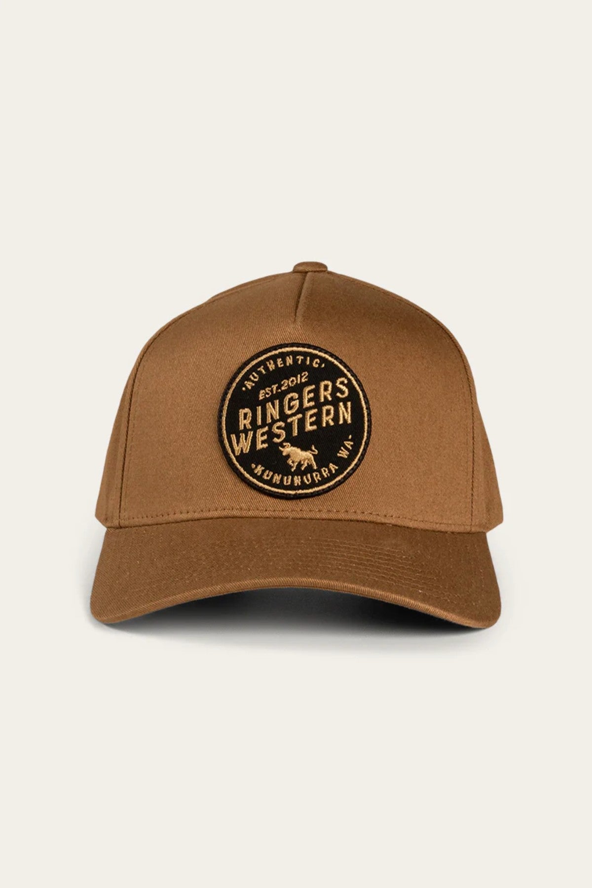 The Ringers Western Rye Baseball Cap features a circular black patch on the front, showcasing the text "Ringers Western," an image of a bull, and the words "Authentic" and "Est. 2012" arranged in a circular design. Made from durable Cotton Twill, this brown cap has a curved brim and an adjustable strap at the back.