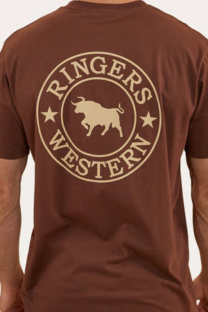 A person wearing a Ringers Western Signature Bull Loose Fit T-Shirt, made from 100% cotton jersey, featuring a large circular "RINGERS WESTERN" logo with a bull and two stars on the back.