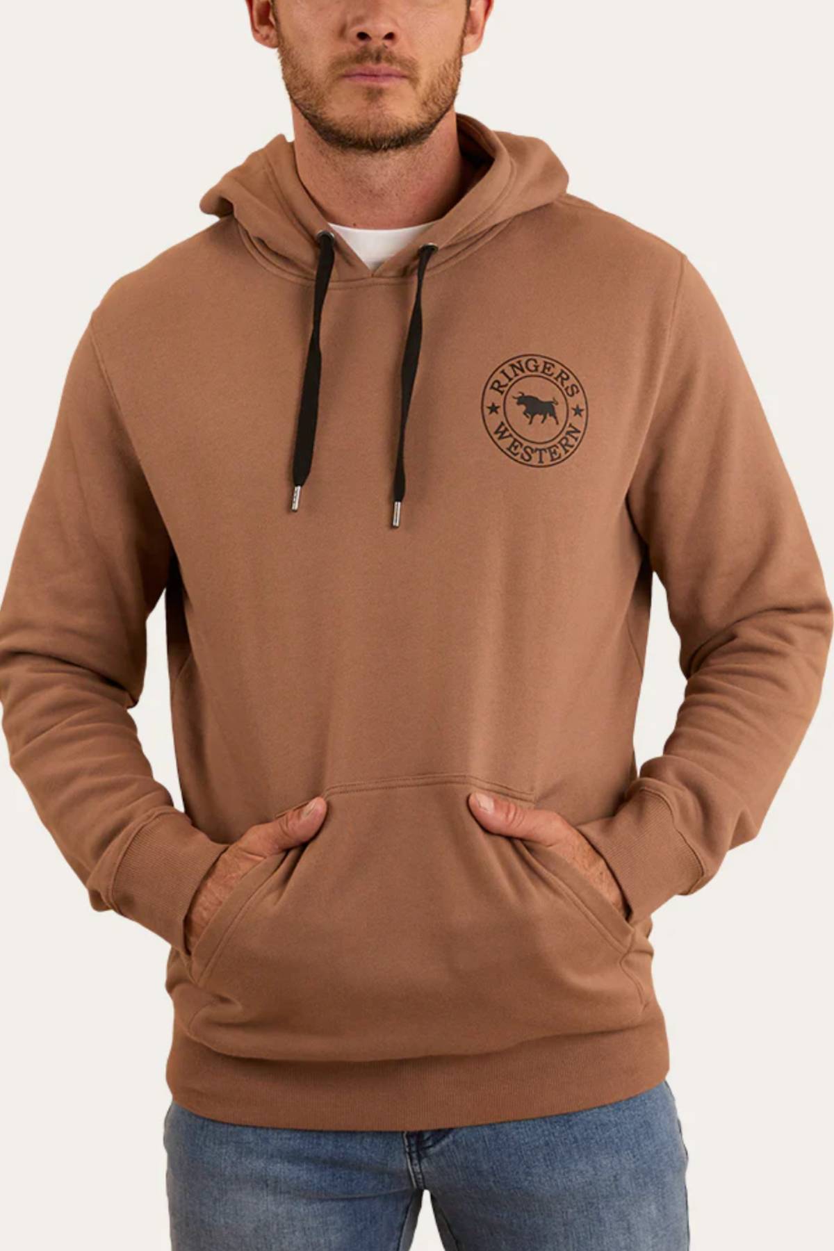 A man wearing a Ringers Western Signature Bull Pullover Hoodie featuring a bull graphic on the chest, paired with blue jeans and standing with his hands in the front pocket.