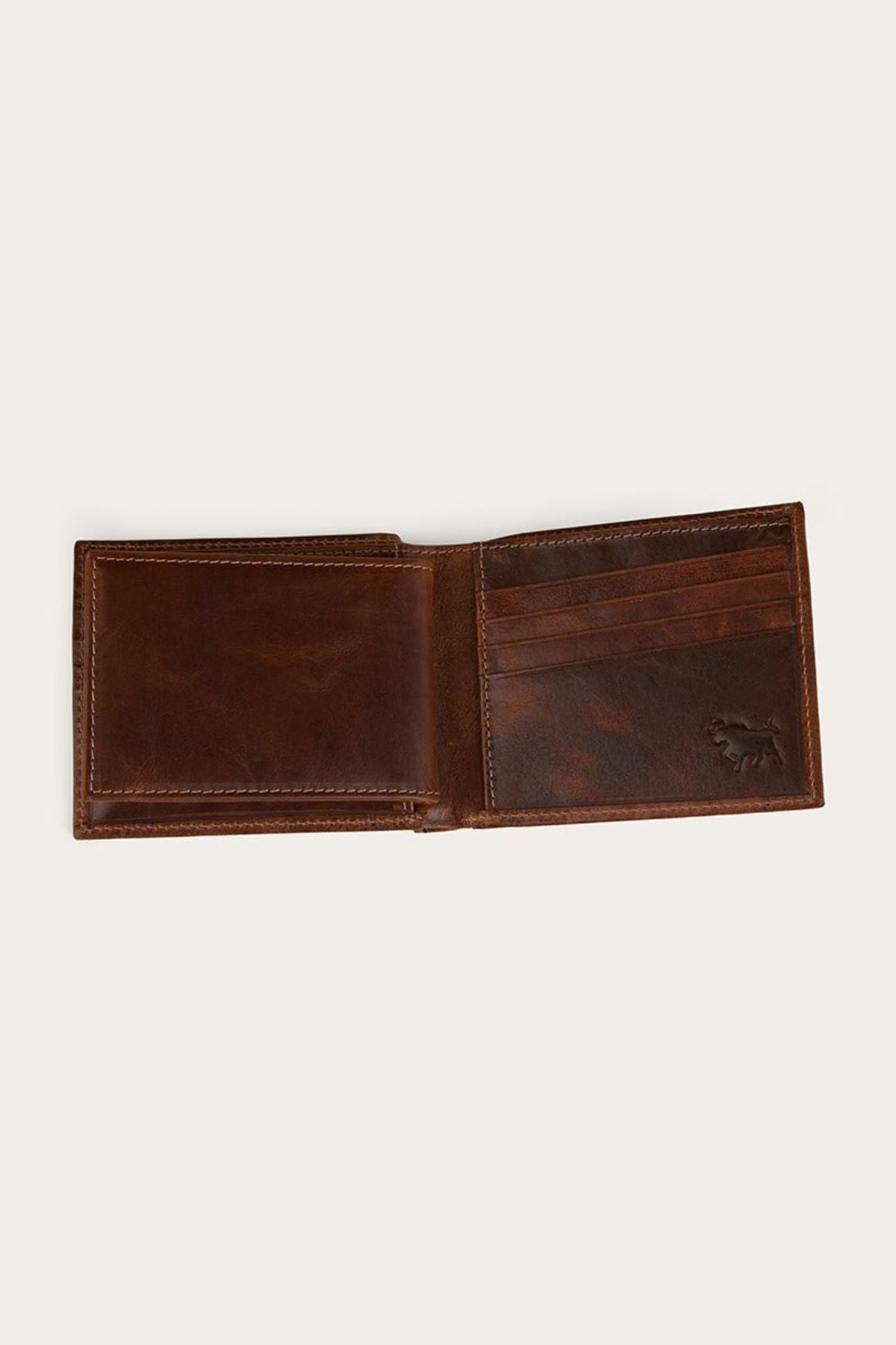 The Ringers Western Toro Biggo Wallet, crafted from brown pull-up leather, is shown open with visible card slots and a small embossed animal logo in the bottom right corner. The empty wallet is displayed against a light background.
