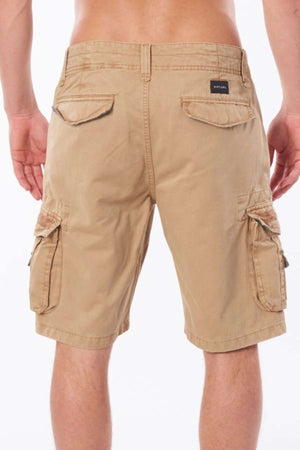 A person stands against a plain white background, wearing the Rip Curl Classic Surf Trail Cargo Short in a relaxed-fit beige style, featuring side and back pockets.