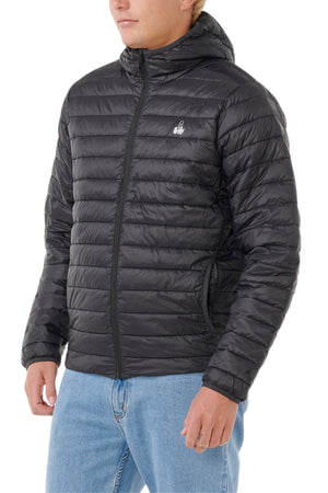 Someone wearing the Rip Curl Anti Series Search Puffer Hood, a black, packable puffer jacket with horizontal quilting, paired with light blue jeans, stands against a white background.