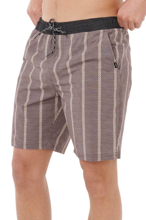 A person wearing Rip Curl Boardwalk Jackson Volley shorts in brown with beige vertical patterns and a black drawstring, hands in pockets. The image is cropped at the torso and knees.