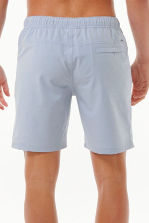 A person wearing Rip Curl Boardwalk Jackson Volley shorts in light blue is shown from the back. The shorts feature an elastic waistband and a single back pocket, crafted from quick-dry fabric. The person stands against a neutral background, ready for any adventure.