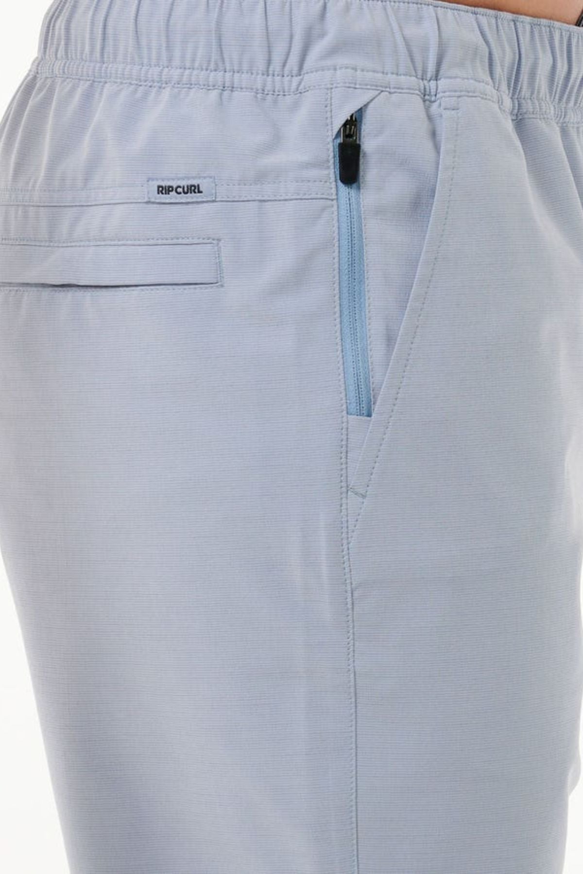 Close-up of the light blue Rip Curl Boardwalk Jackson Volley pants showcasing an elastic waistband, a zippered pocket, and a back pocket. A small "Rip Curl" logo tag is located near the waist. The quick-dry fabric feels smooth and comfortable, ideal for any adventure.