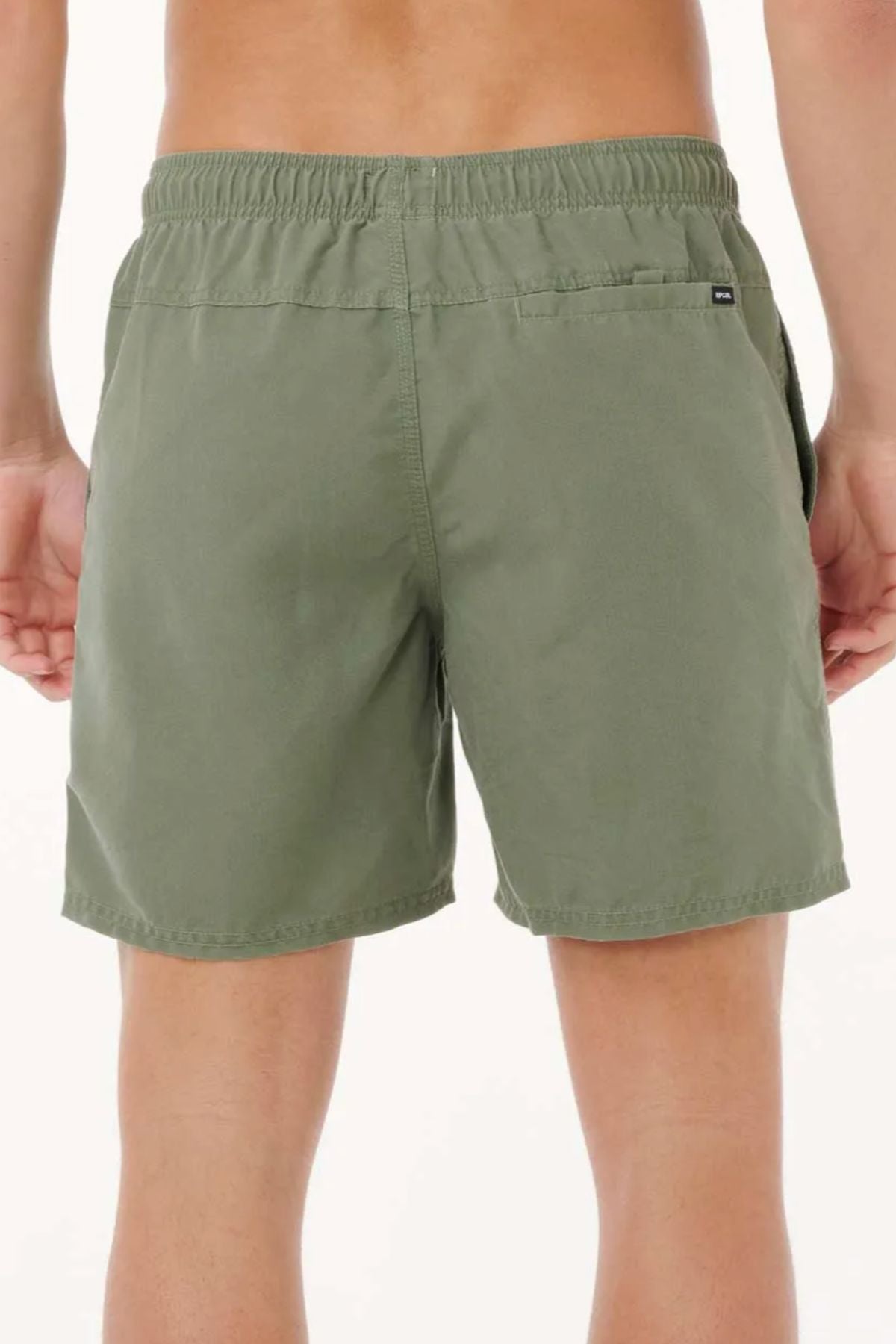 A person is shown from behind wearing Rip Curl Bondi Volley board shorts in olive green, made with recycled PET. The shorts have an elastic waistband and a small right-side pocket. The background is plain and light-colored.