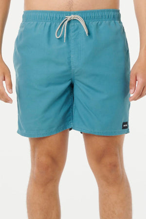Someone wears teal Rip Curl Bondi Volley board shorts with a white drawstring, made from recycled PET, standing against a plain white background. Only their torso and legs are shown; the face is not visible.