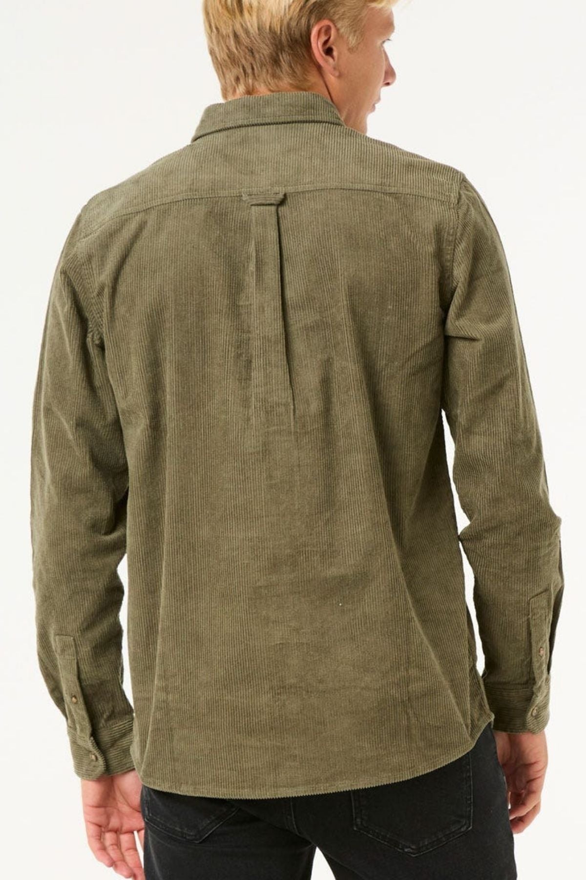 A man with short blond hair is seen from the back, wearing an olive green Rip Curl Classic Surf Cord Shirt and black pants, set against a plain white background.