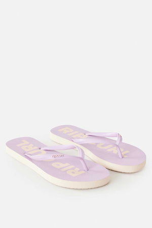 The Rip Curl Classic Surf Bloom Thongs, featuring thin straps in light purple, are showcased on a plain background. Designed as sustainable footwear, the soles are crafted from BLOOM algae-blended foam and display the "Rip Curl" brand name in beige text. One sandal is positioned slightly ahead of the other.
