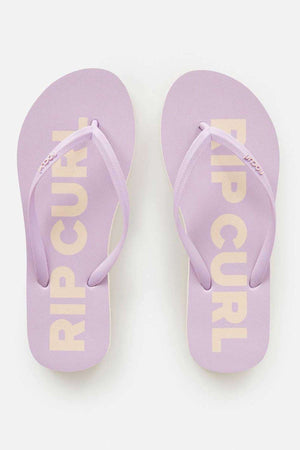 The Rip Curl Classic Surf Bloom Thongs in lavender feature "RIP CURL" in yellow on each sole. Made with BLOOM algae-blended foam, they have textured straps and a minimalist design, showcased against a plain background.