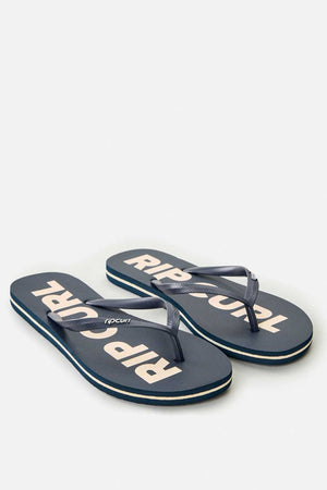 The Rip Curl Classic Surf Bloom Thongs in navy blue feature white "RIP CURL" lettering on the soles. They come with ergonomic molded straps and a textured footbed crafted from BLOOM algae-blended foam, diagonally positioned to prominently showcase the branding.