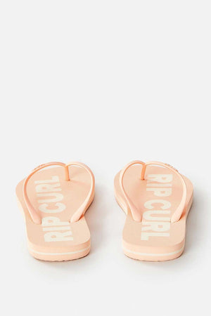 A pair of Rip Curl Classic Surf Bloom Thongs in pale pink, crafted for sustainable comfort with BLOOM™ algae-blended foam EVA, and showcasing white text on the footbed, is displayed from the back against a plain background.