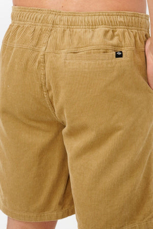 Close-up of the back of a person wearing Rip Curl Classic Surf Cord Volley shorts, featuring an elastic waistband and back pocket. The right hand is partially tucked in, highlighting the retro, vintage-inspired surfing style.