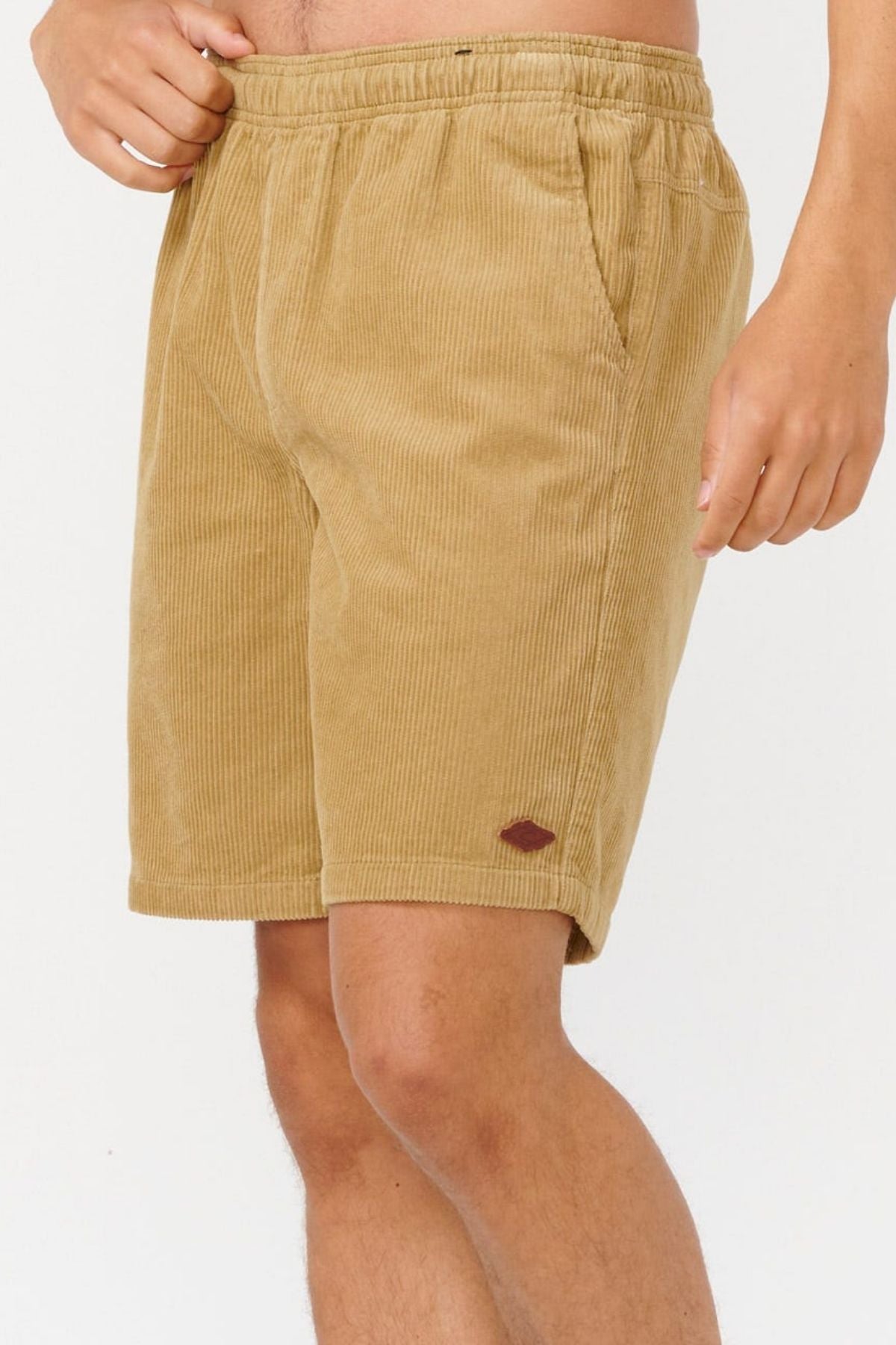 A person wearing Rip Curl Classic Surf Cord Volley shorts, featuring an elastic waistband and side pockets, stands against a plain white background with only their lower torso and legs visible.