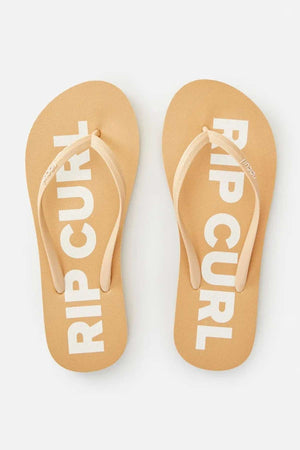A pair of beige Rip Curl Classic Surf Thongs, featuring "RIP CURL" prominently displayed on the ergonomic molded straps and soles, are positioned side by side on a light background.
