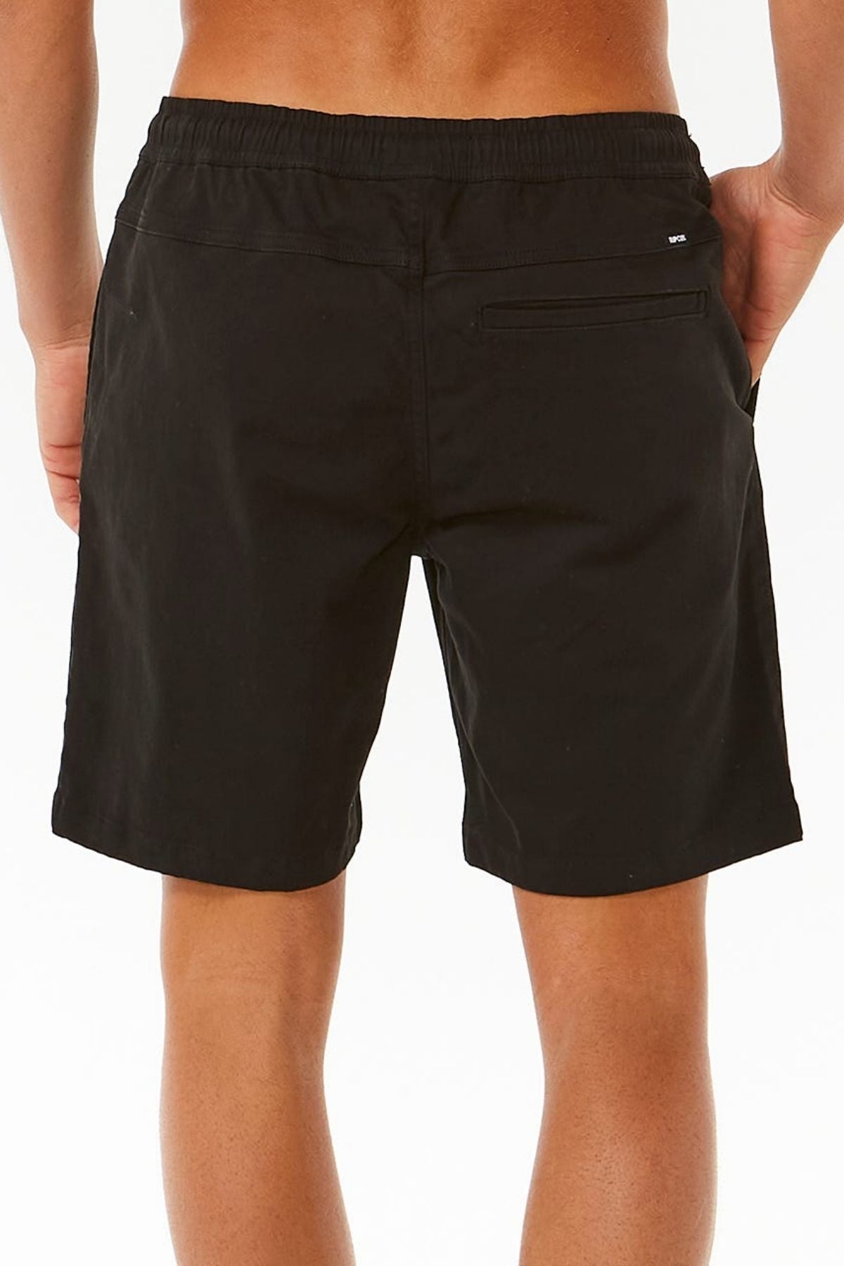 A person stands with their back to the camera, wearing Rip Curl Classic Surf Volley men's shorts with an elastic waistband and a single back pocket, set against a plain white background.
