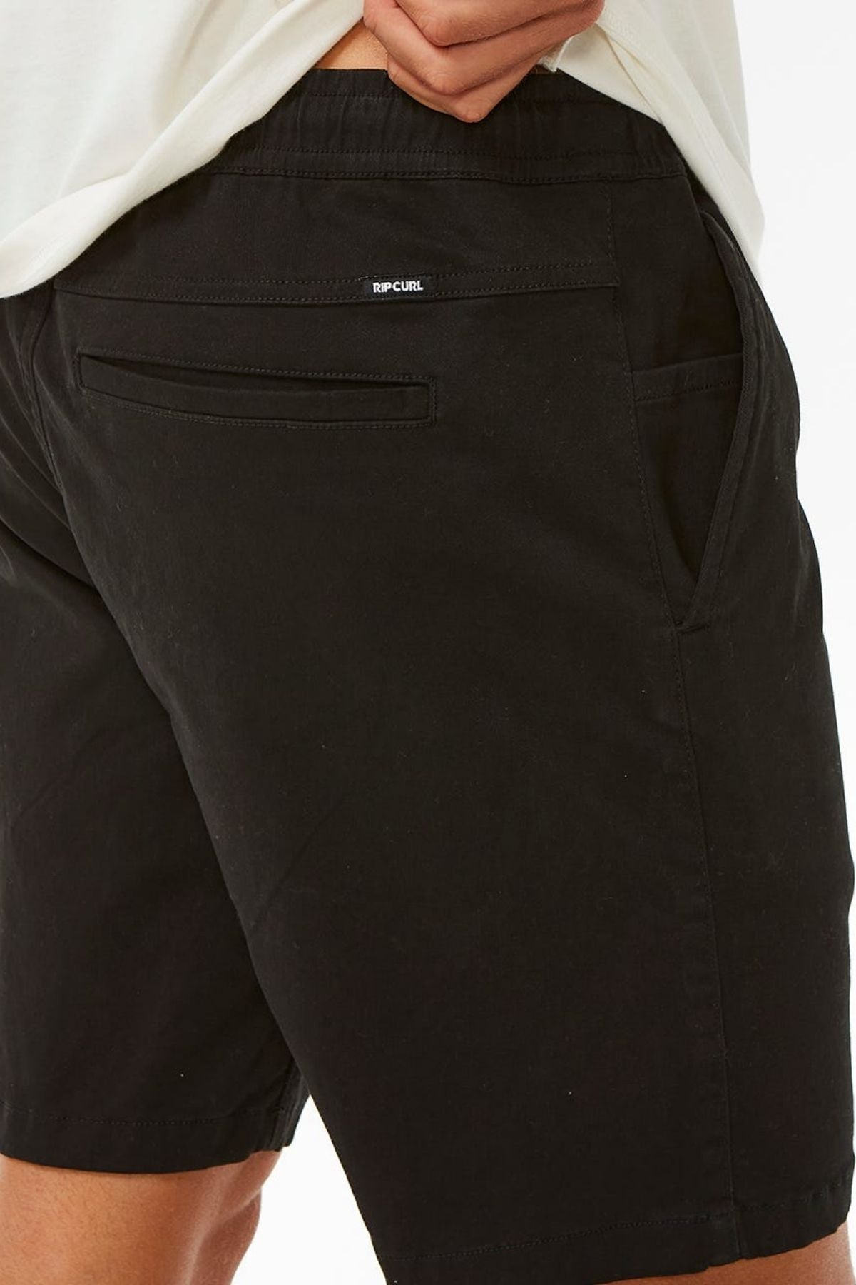 A person wearing black Rip Curl Classic Surf Volley shorts with a flexible fit and one hand in the pocket, shown from the waist down against a white background.