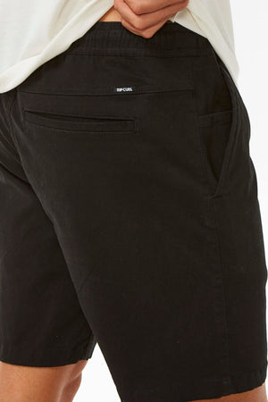 A person wearing black Rip Curl Classic Surf Volley shorts with a flexible fit and one hand in the pocket, shown from the waist down against a white background.
