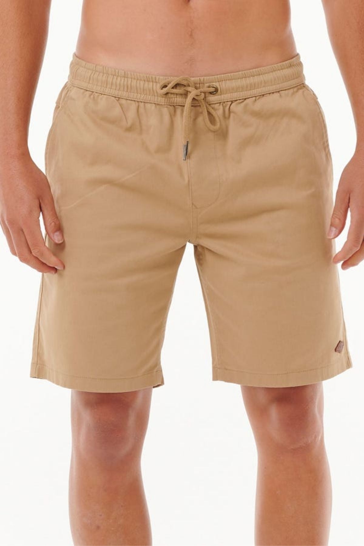 Someone is wearing the Rip Curl Classic Surf Volley shorts in light brown, knee-length cotton, featuring an elastic waistband and adjustable drawcord, standing against a plain background.