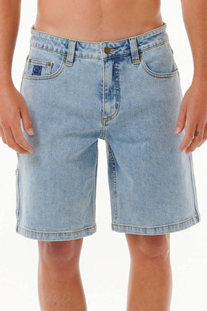 A person wears Rip Curl Dosed Denim Walkshorts in light blue 90s style cotton denim with five pockets and a button closure, standing against a plain white background and leaving their torso bare.
