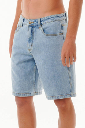 A person wearing Rip Curl Dosed Denim Walkshorts in light blue stands against a plain white background. The shorts have pockets and a button closure. Only the lower torso and upper legs are visible.