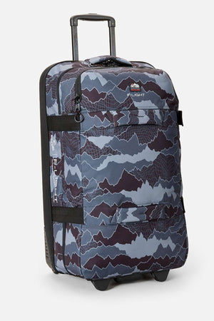 The Rip Curl F-Light Global 100L Search Camo Travel Bag, made from recycled polyester with a blue and gray camo print and retractable handle, stands upright on a light background—perfect for eco-conscious travelers.