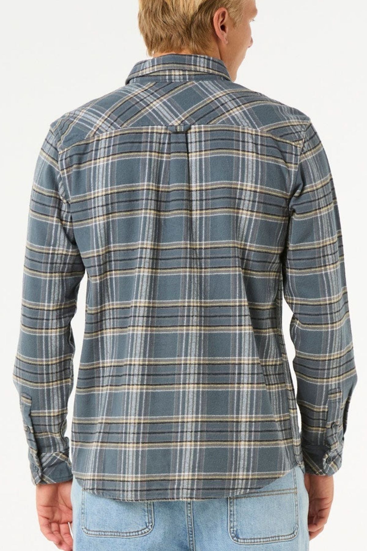 A person with short blond hair is seen from the back in a Rip Curl Griffin Flannel Shirt, featuring blue and gray plaid and buttoned chest pockets, paired with light blue jeans, against a plain white background.