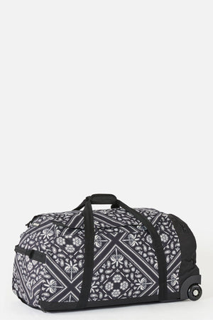 The Rip Curl Jupiter 80L Mixed Travel Bag features a black, recycled polyester build with white floral and geometric patterns, sturdy black handles, side pocket, and two wheelsβideal for travelβshown against a plain white background.