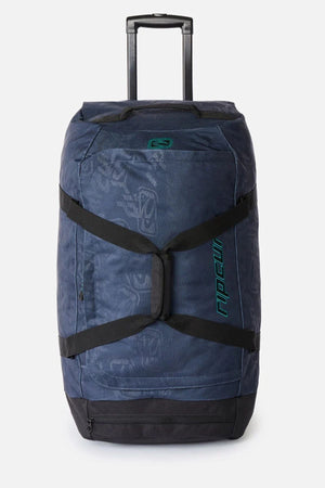 Navy blue Rip Curl Jupiter Archive 80L rolling duffel bag featuring a retractable handle, black straps, and a repeating pattern.
