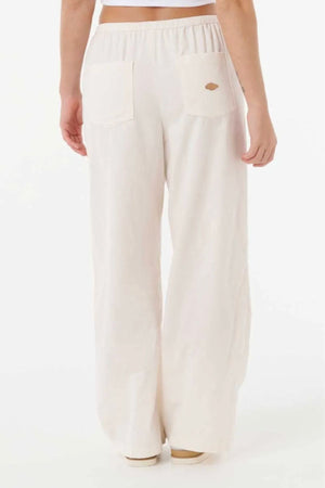 A person models the Rip Curl Keepsakes Washed Cord Pant—loose-fitting, high-waisted white cotton corduroy pants with two back pockets—shown from the waist down against a plain white background.