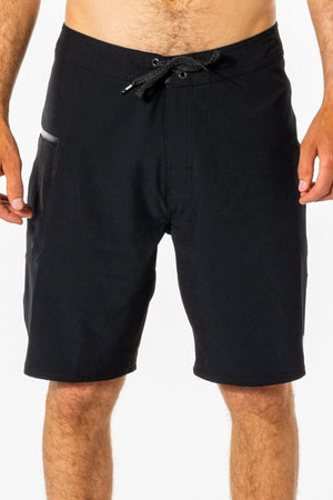 A man is wearing Rip Curl Mirage Core Boardshorts, featuring black quick-dry fabric, a drawstring waist, and a side pocket, while standing against a plain white background.
