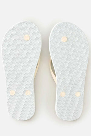 A pair of Rip Curl Mixed Bloom Thongs are shown from the bottom, featuring textured white rubber soles with four circular grip points on each and a classic 3-point design. The light-colored straps are barely visible from this angle.