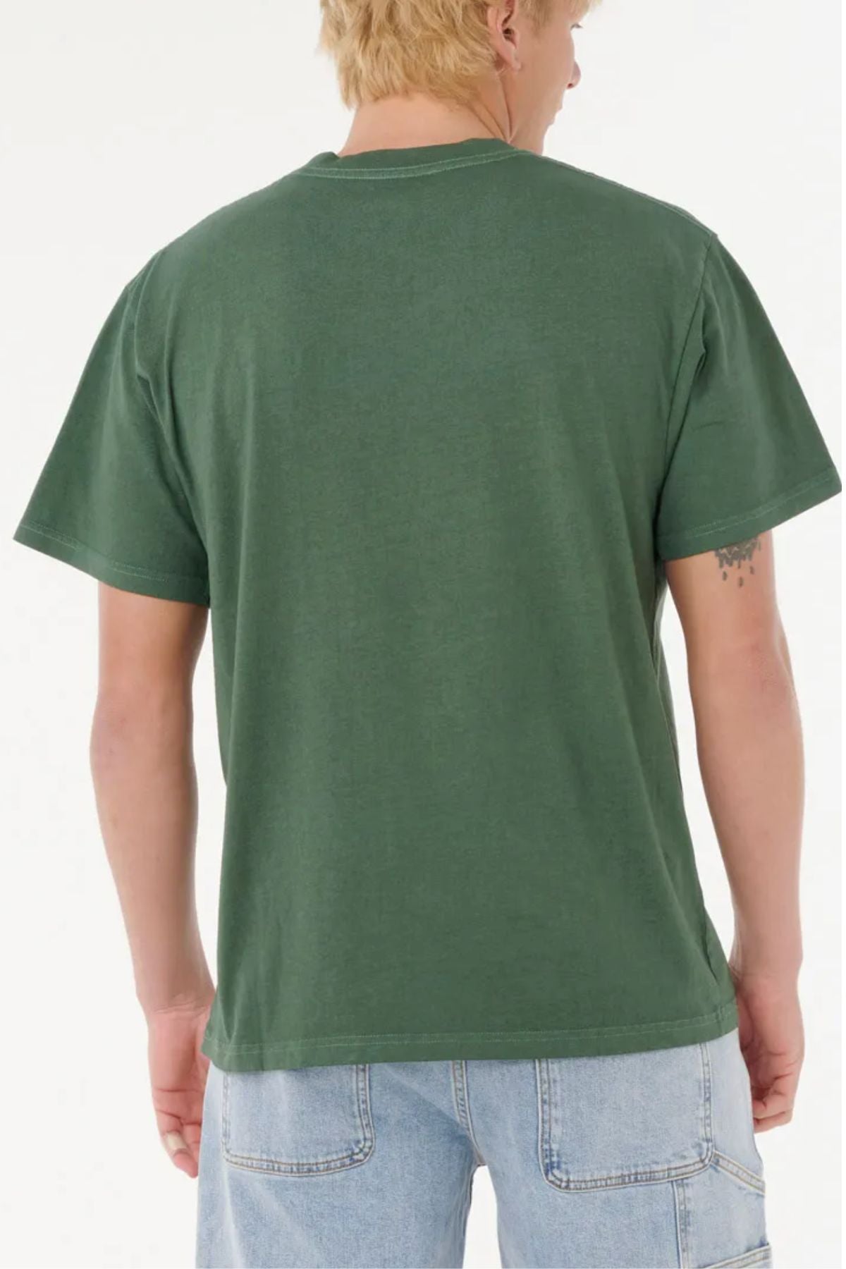 A person with short blond hair is seen from behind wearing a green Rip Curl Nu Dosed Tee and light blue denim shorts against a plain white background.