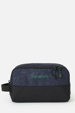 A navy blue and black Rip Curl Archive Groom Toiletry Bag with a side handle, a zippered top, and a green logo.