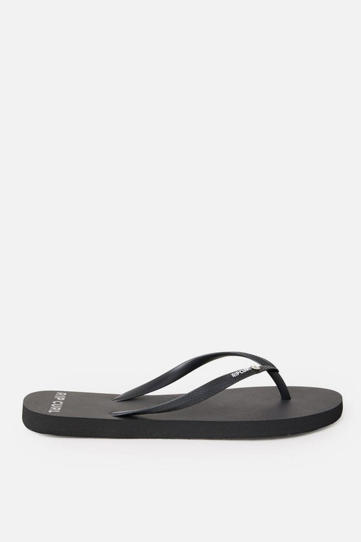 A single black Rip Curl Premium Surf Bloom Thong with a simple design. The footbed is flat and made of a smooth material, while the strap is thin and also black. The brand name "Rip Curl" is visible in white letters on the strap and near the heel of the footbed. The background is white.