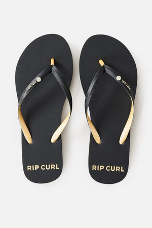 A pair of Rip Curl Premium Surf Bloom Thongs in black, featuring "RIP CURL" written in white on each footbed. The straps are black with a metallic silver button at the center, and the left strap also displays the brand name "RIP CURL" in white.