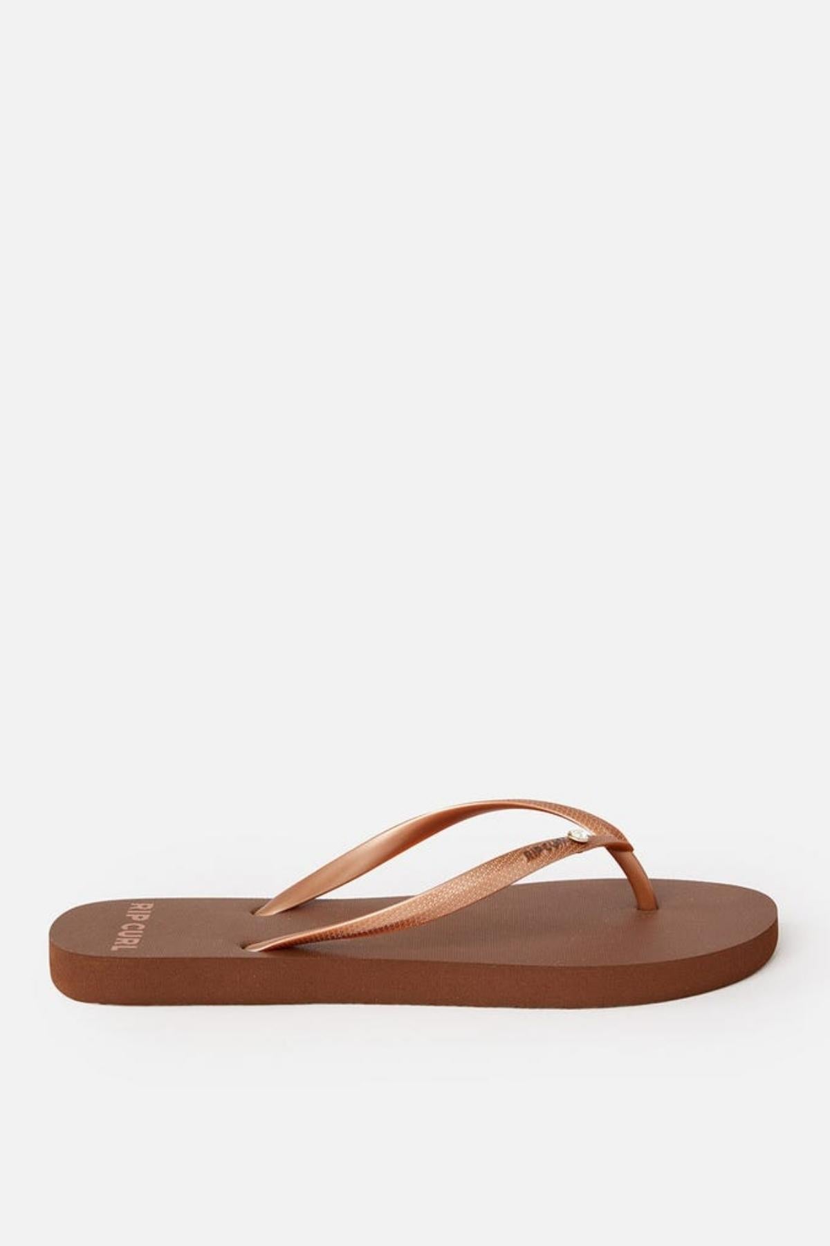 A single Rip Curl Premium Surf Bloom Thong, featuring a metallic light-bronze strap and a brown color, is displayed against a plain white background. The thong has a simple design with a flat sole.