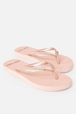 The Rip Curl Premium Surf Bloom Thongs are light pink flip-flops featuring a simple design. Both the footbeds and straps are pink, with the straps showcasing a small metallic detail. The "Rip Curl" branding is visible on the footbeds near the heels, all set against a white background.