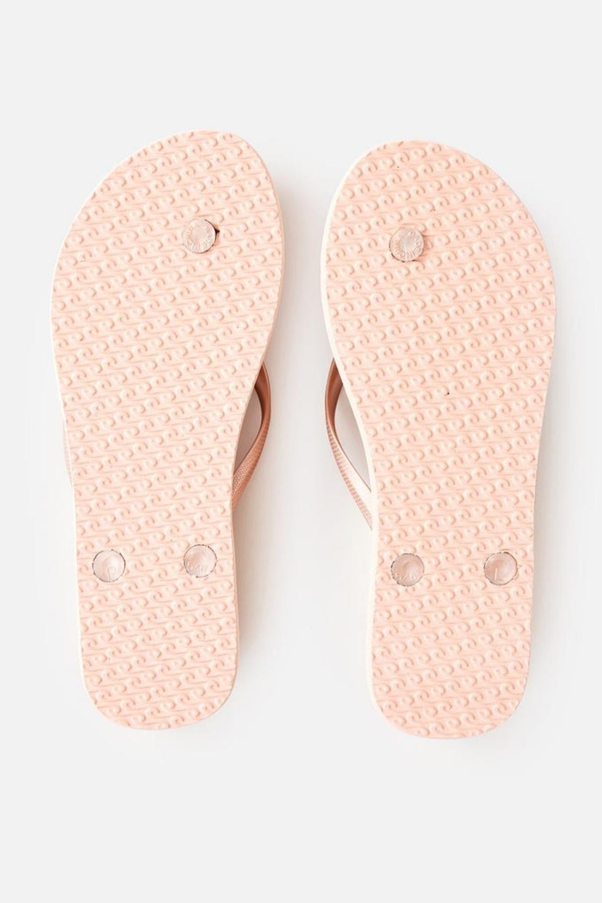 The image shows the bottom view of a pair of Rip Curl Premium Surf Bloom Thongs placed side by side on a white background. The pink soles have a textured pattern and circular indentations, likely for grip or branding purposes. The straps are also visible on the upper part.