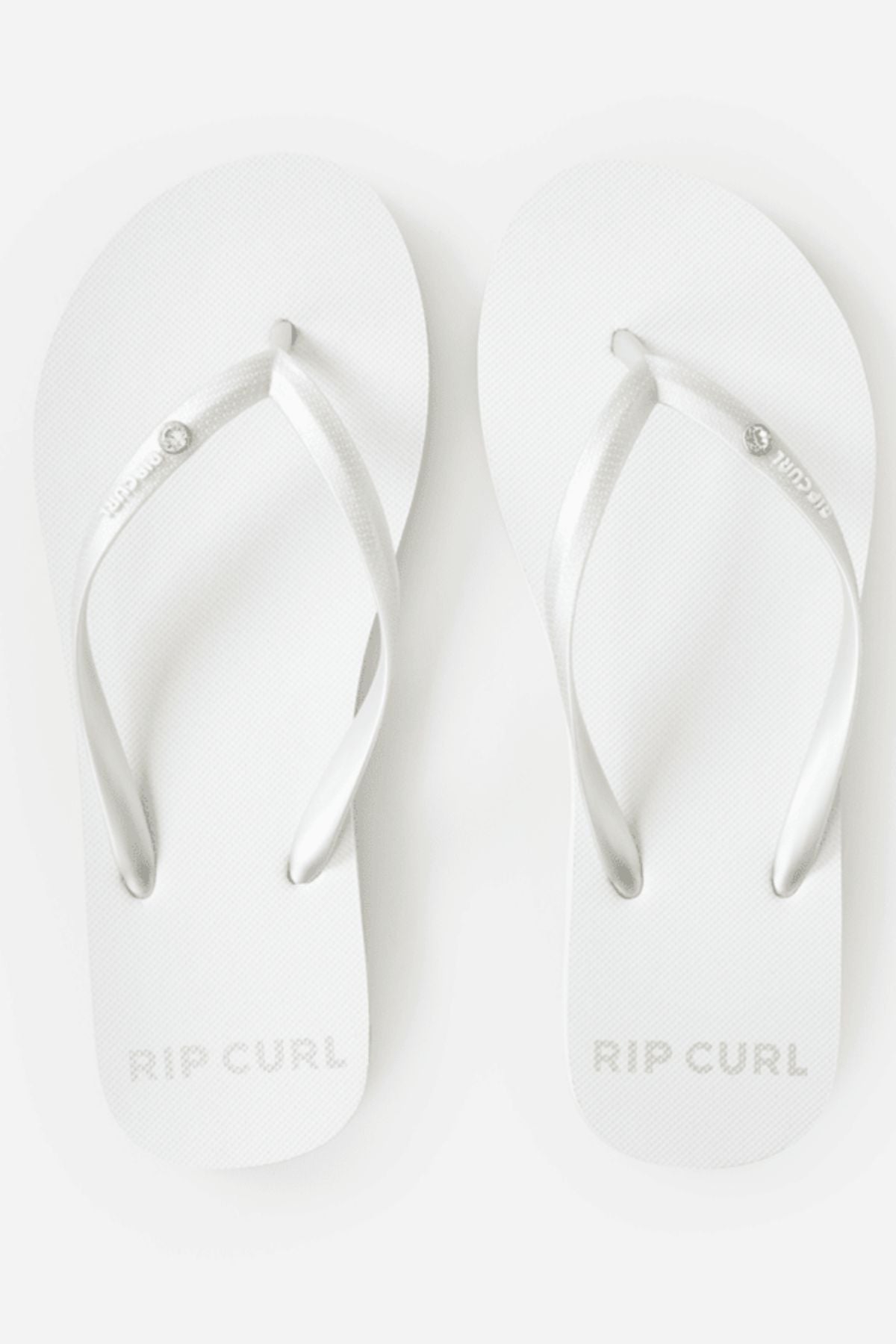 A pair of Rip Curl Premium Surf Bloom Thongs in white with silver straps, viewed from above on a white background. The Rip Curl logo appears on the footbeds and strap—ideal stylish, relaxed footwear for the beach.