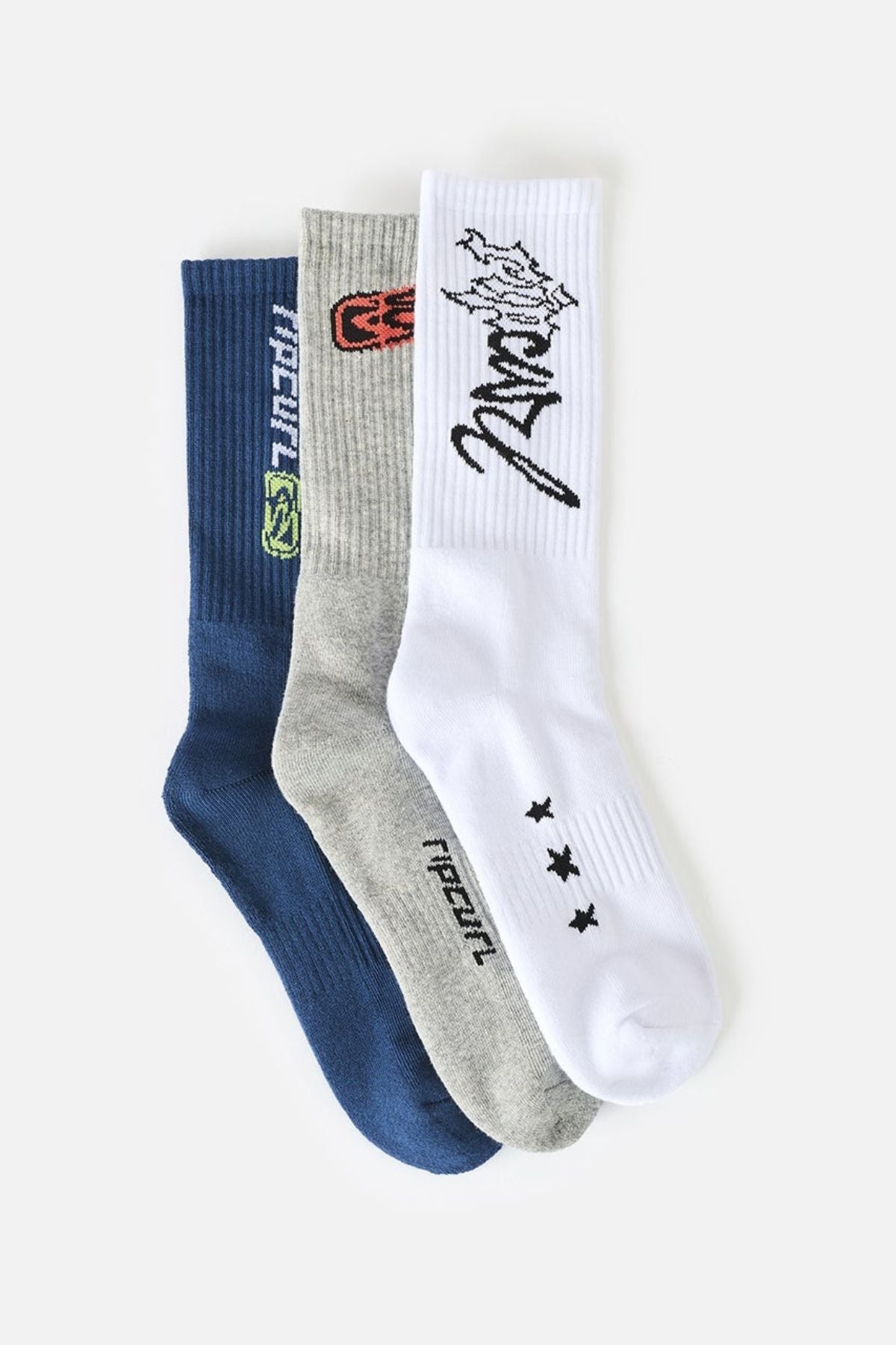 Three pairs from the Rip Curl Retro Crew Sock 3 Pack—one blue, one gray, and one white—each featuring unique graphic designs and text, are laid side by side on a plain white background. Designed for comfort, these crew socks offer a cushioned footbed and arch support for all-day wear.