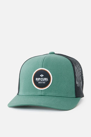The Rip Curl Routine Curve Trucker is a green and black trucker cap featuring a round "Rip Curl" logo patch on the front, making it an ideal choice for any outdoor activity. It boasts a green front panel and bill, paired with a black mesh back and adjustable snapback closure.