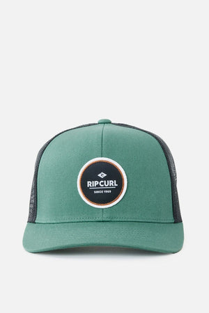 The Rip Curl Routine Curve Trucker is a green trucker cap with a black mesh back and a round logo patch on the front that reads "Rip Curl Since 1969," making it perfect for any outdoor activity.