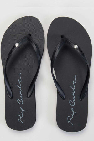 The sophisticated Rip Curl Script Wave Bloom Thongs showcase a textured sole made from BLOOM™ algae-infused foam EVA. Their black straps are embellished with delicate white gemstones, while "Rip Curl" is elegantly scripted in cursive across each open-toe Zori sole.