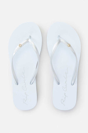 The Rip Curl Script Wave Bloom Thongs are a stylish pair of white flip-flops featuring silver straps and a delicate gold embellishment near the toes, crafted with Zori construction. The brand name is elegantly scripted on the footbed for an added touch of sophistication.