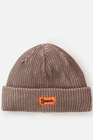 The Rip Curl Search Chunky Reg Beanie is a brown ribbed knit hat with a folded brim, featuring an orange rectangular patch on the front displaying "Search" in black text.