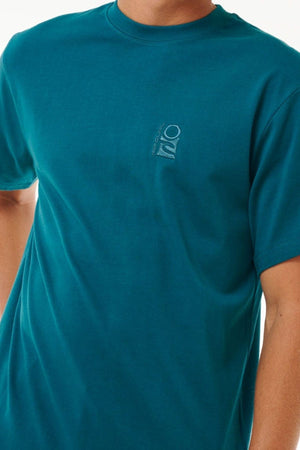 Someone wearing a Rip Curl Search Embroidery Tee in teal with rolled-up sleeves and a small chest logo, offering comfort and style with its cotton fabric.