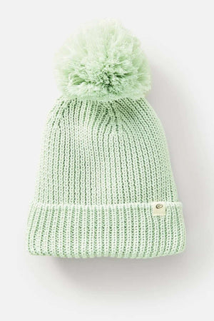 The Rip Curl Sol Seeker Pom Pom Beanie, available in light green, is made from recycled polyester and features a large pom-pom on top with a folded brim. A circular metal tag adorns the brim, highlighting its eco-friendly style against a plain white background.