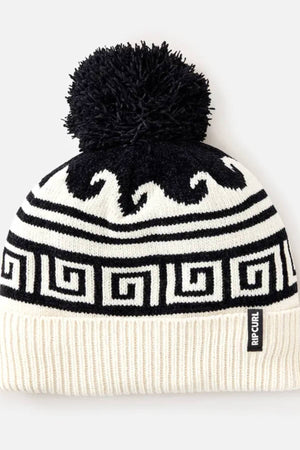 The Rip Curl Soleil Regular Pom Pom Beanie features a black pom-pom, white background with black intarsia wave and geometric patterns, ribbed brim, and a small Rip Curl label.