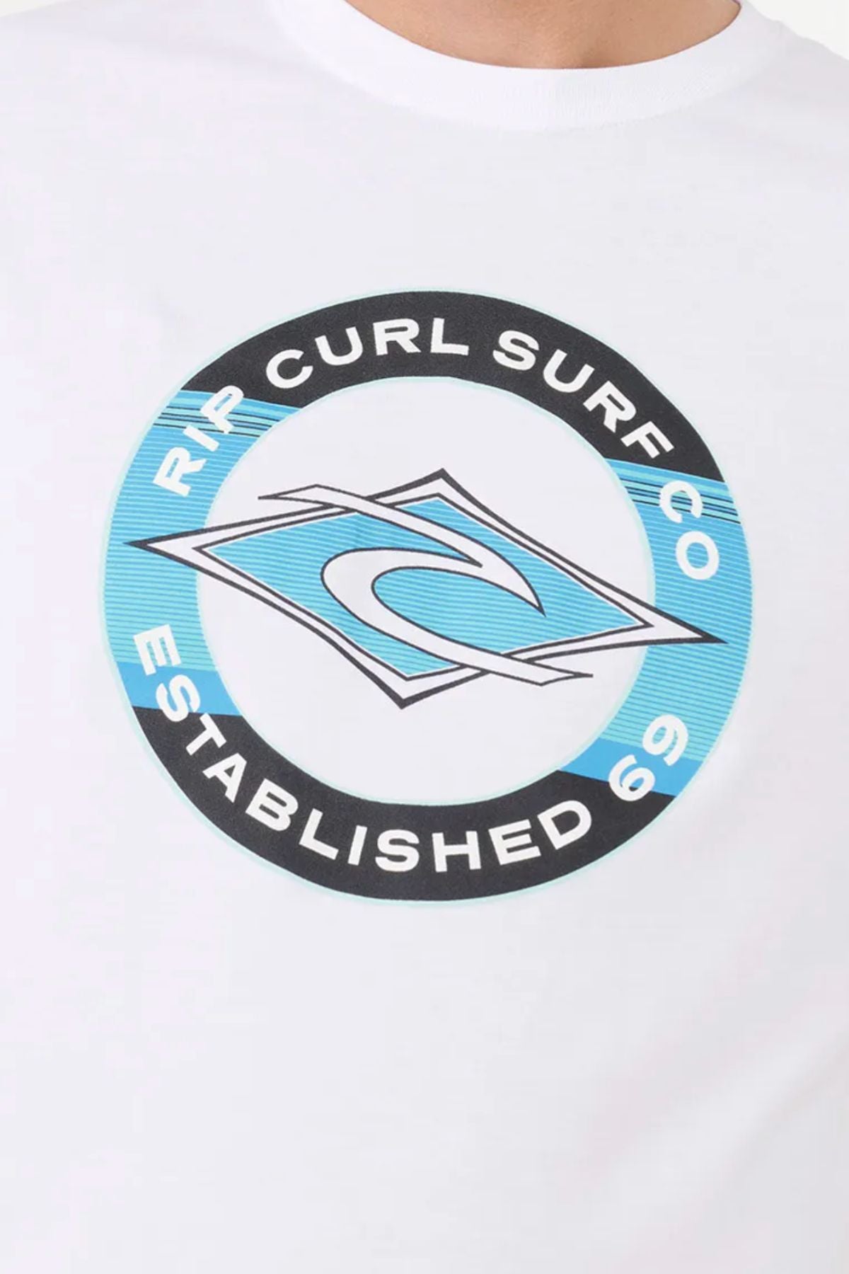 The Rip Curl Staple Filler Tee features a circular Rip Curl Surf Co. logo with a stylized wave inside a diamond on blue, “Established 69” text, and is crafted from soft cotton jersey for men.